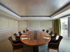 A conference room with a round table, chairs, and a projector screen. - Four Seasons Astir Palace Hotel Athens (Vari-Voula-Vouliagmeni)