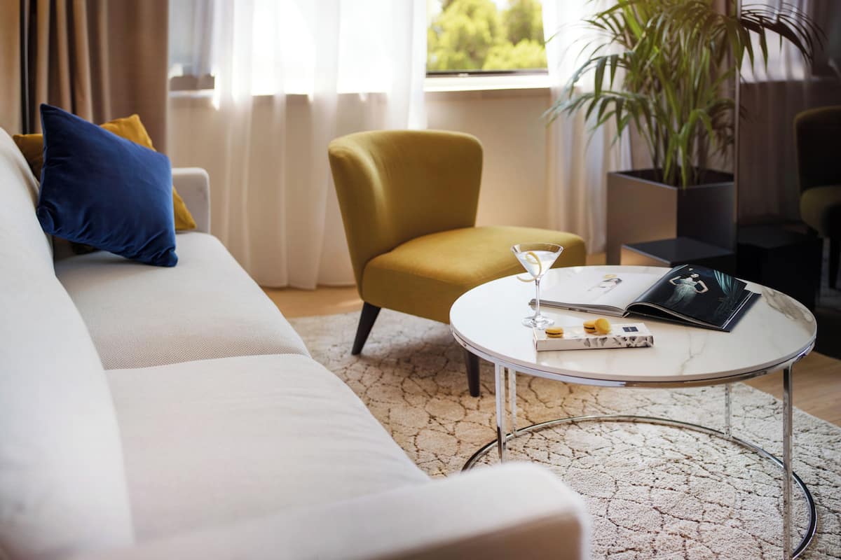 Uma sala de estar com sofá, poltrona, mesa de centro e um vaso de planta.