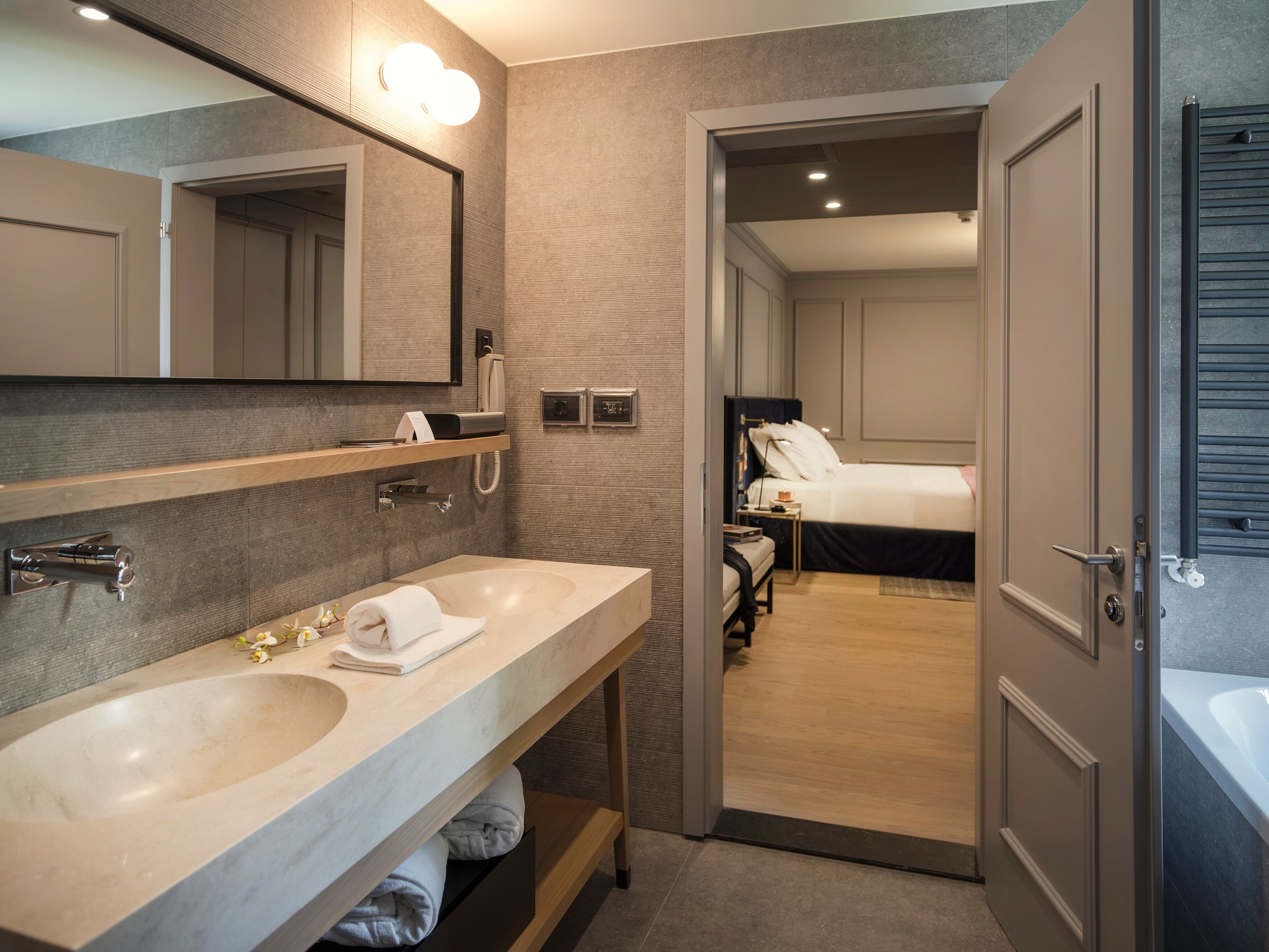 A modern bathroom with dual sinks, a large mirror, and a separate shower area.