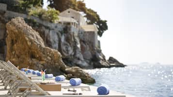 En la playa, sillas reclinables de playa, sombrillas, toallas de playa