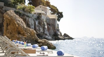 Na praia, espreguiçadeiras, guarda-sóis, toalhas de praia 