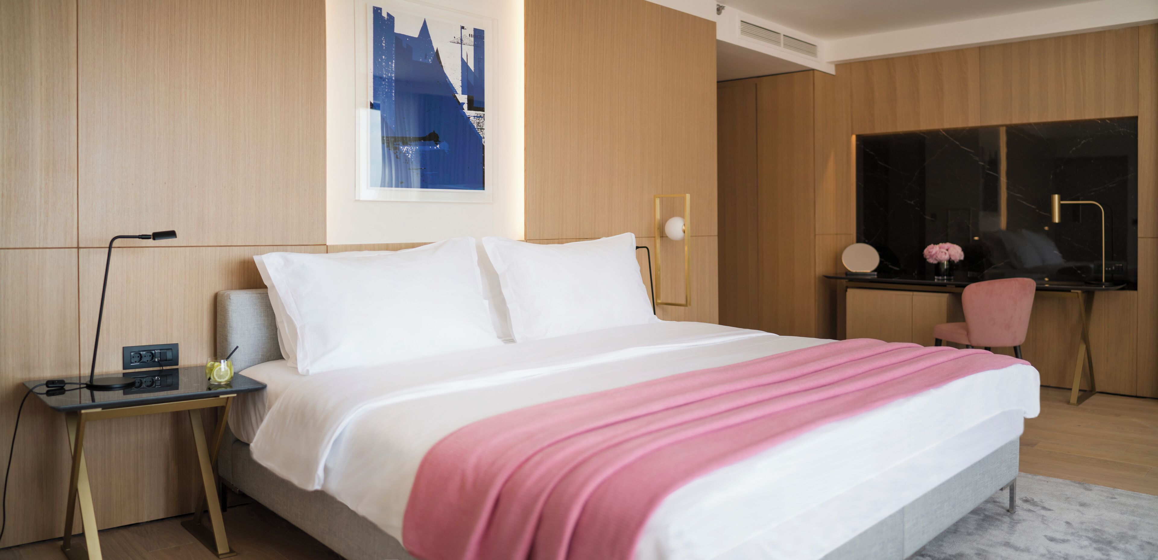 Une chambre d’hôtel moderne avec un grand lit, un bureau, une chaise et une grande fenêtre.