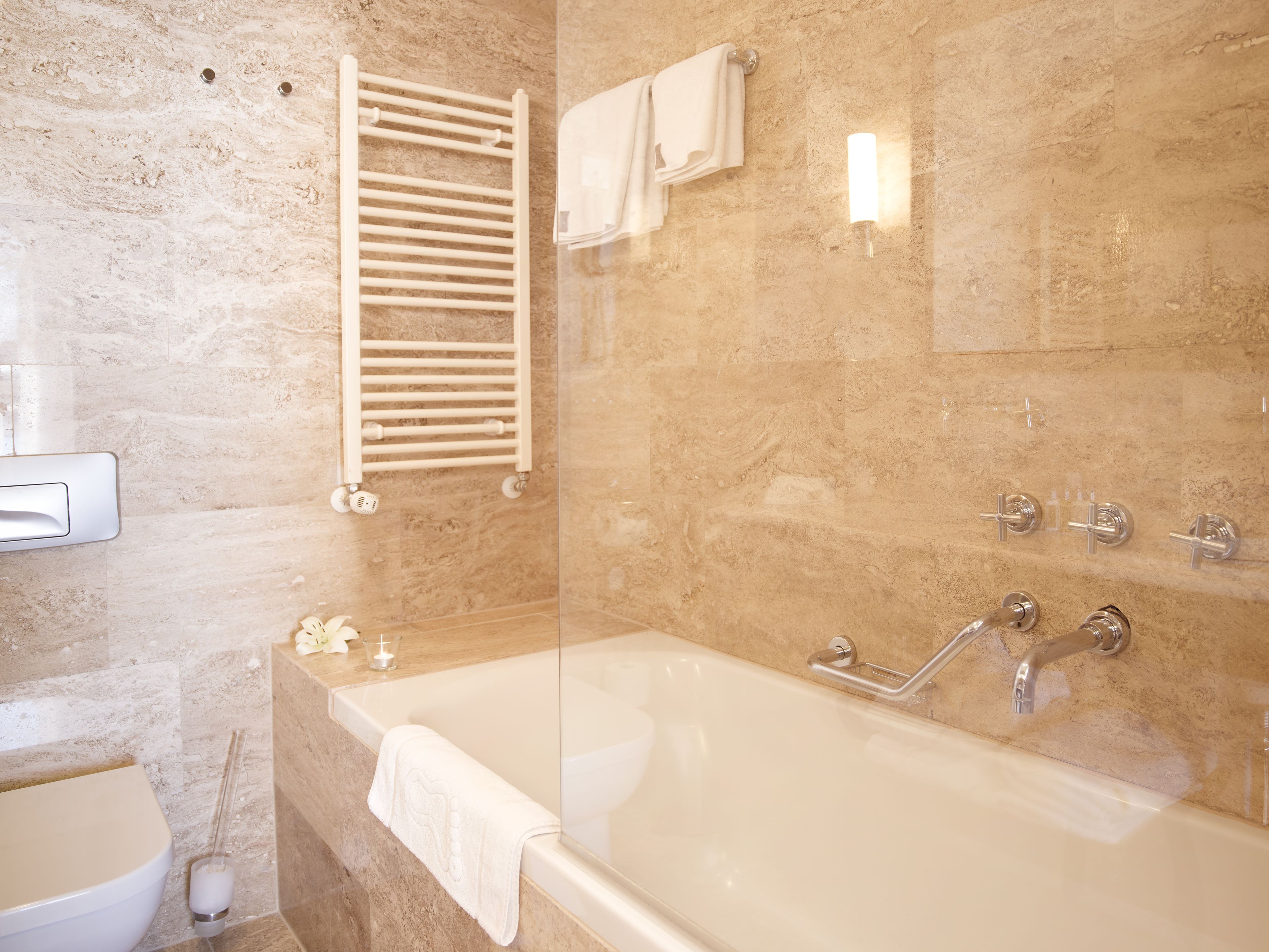 A bathroom with a bathtub, a towel rack, a toilet, and a shower area.