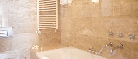 A bathroom with a bathtub, a towel rack, a toilet, and a shower area.