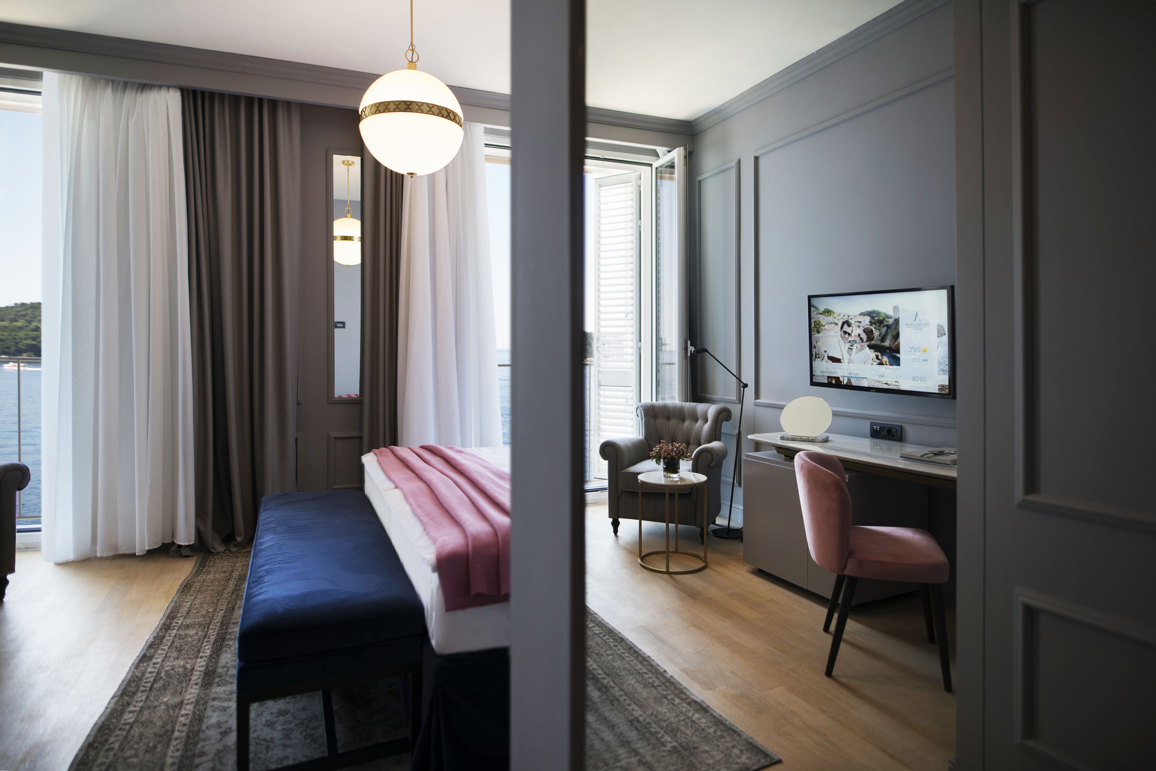 Quarto de hotel moderno com uma cama, uma escrivaninha, uma cadeira e uma televisão.