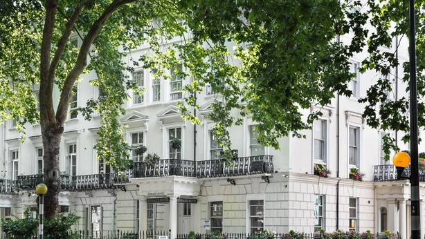 A multi-story building with a classic architectural style, featuring a balcony with black railings and flower boxes. - Edward Hotel Paddington (London)