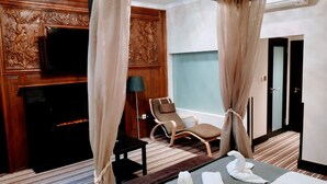 A hotel room with a bed, a chair, a TV, and a fireplace. - Edward Hotel Paddington (London)