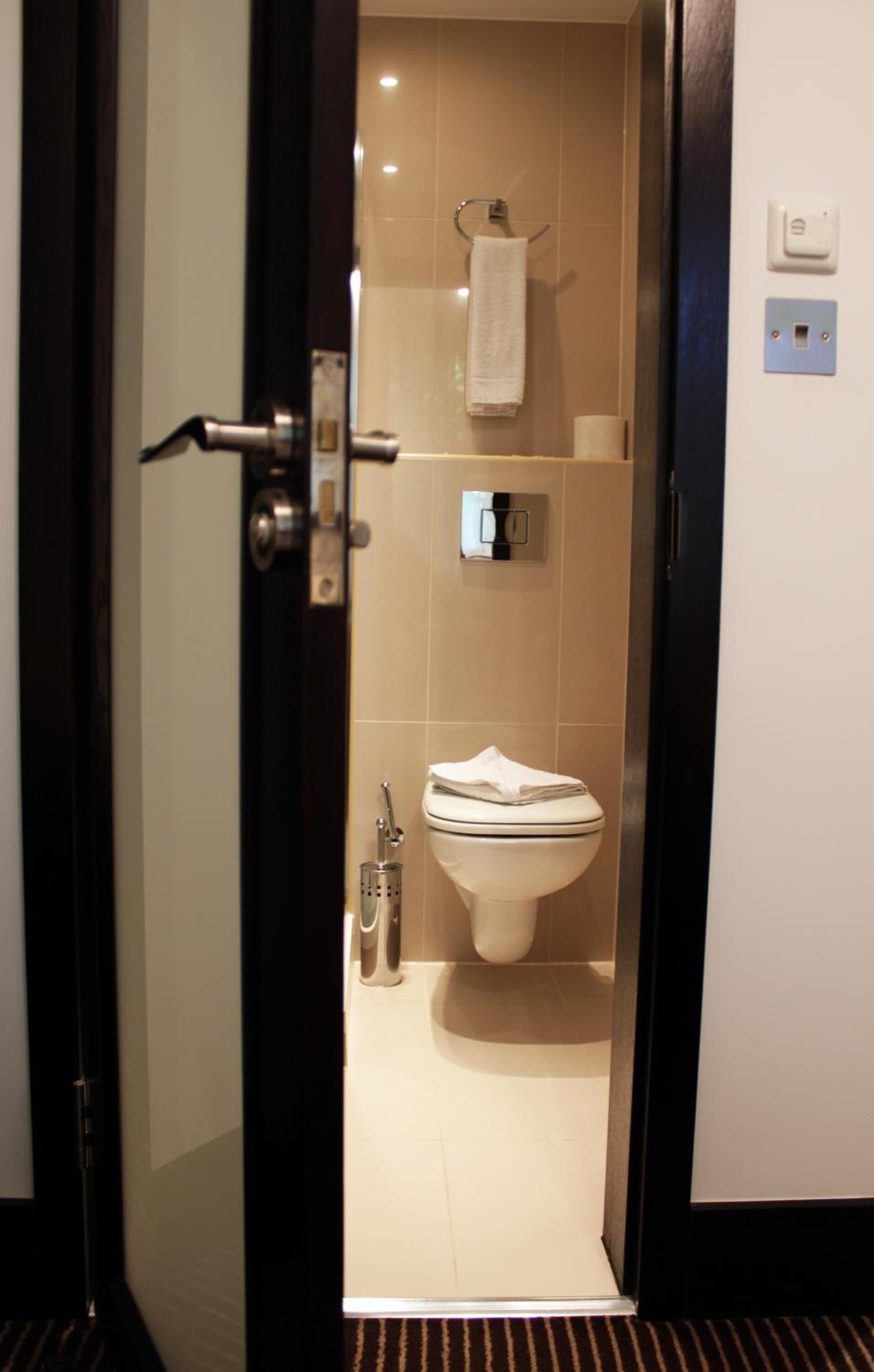 A modern bathroom with a toilet, a towel rack, and a shower area.
