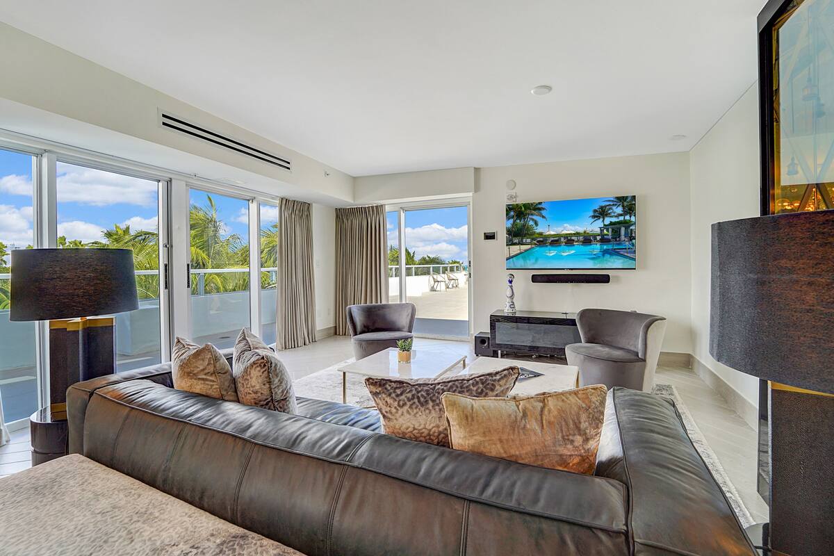 A modern living room with a leather sofa, a coffee table, and a flat-screen TV mounted on the wall.