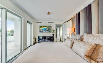 A modern living room with a grey sofa, a white coffee table, and a view of a balcony with plants. at The Sagamore Hotel South Beach - An All Suite Hotel