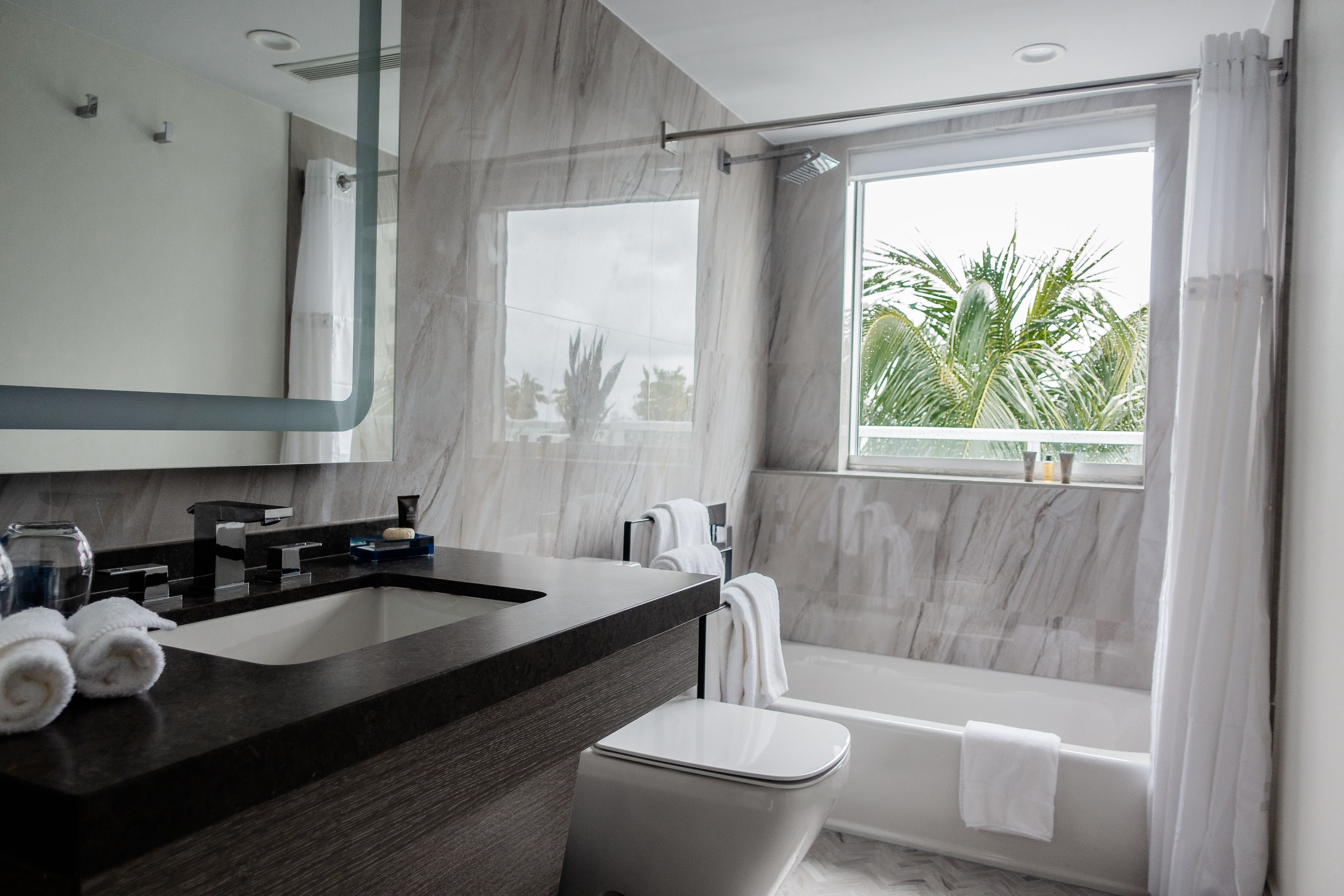 A modern bathroom with a large sink, mirror, and bathtub.