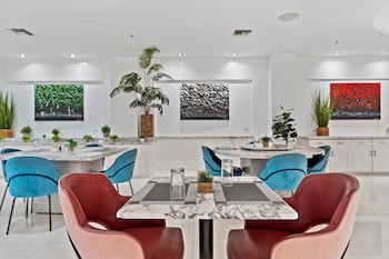 A modern dining area with a glass-top table, black chairs with gold accents, and a chandelier. at The Sagamore Hotel South Beach - An All Suite Hotel