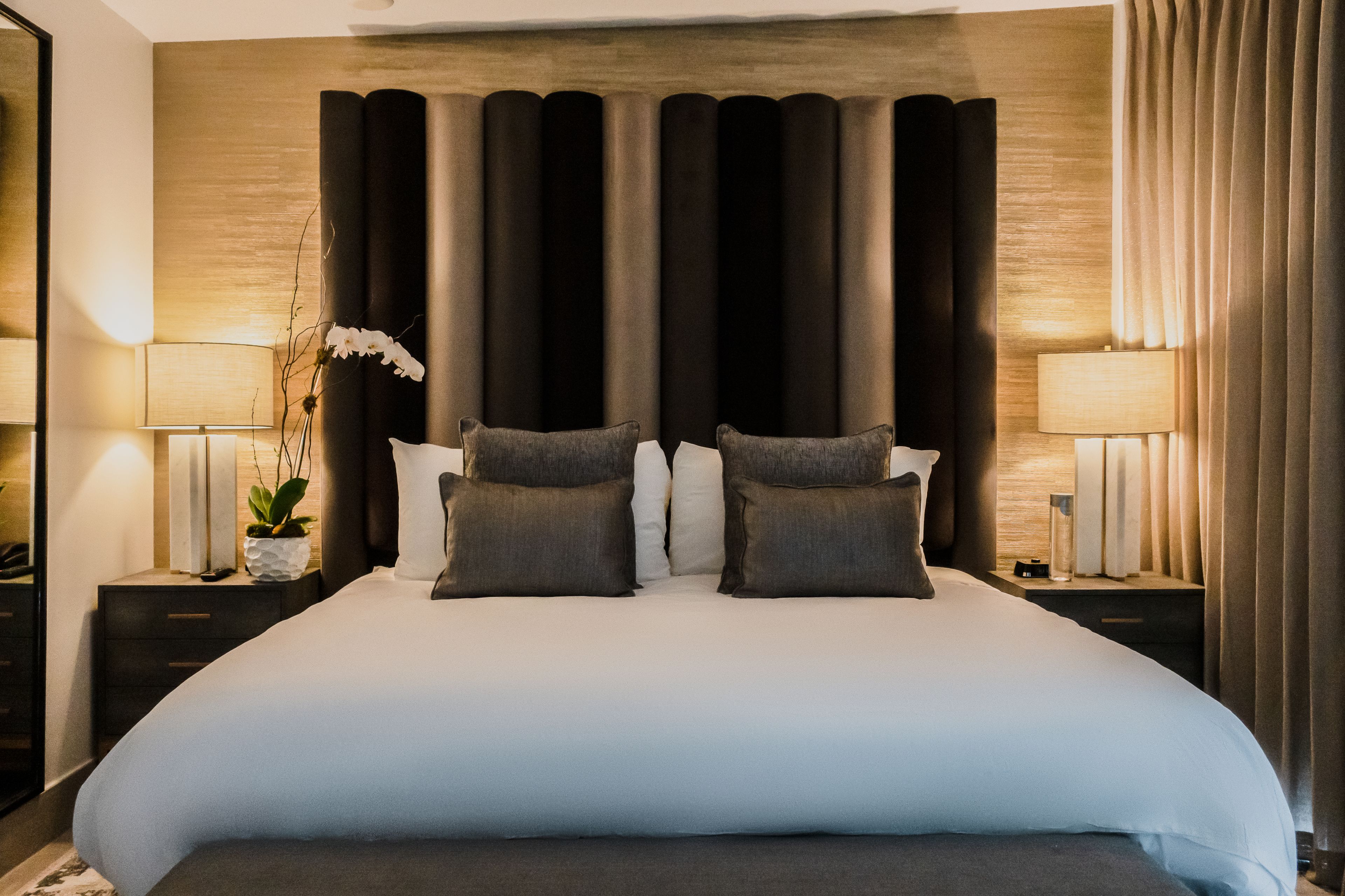 A large bed with a headboard, two bedside tables, and lamps.