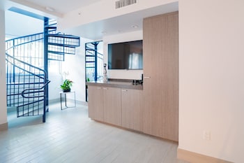 A long, narrow hotel corridor with a series of doors on one side and a row of lights on the ceiling. at The Sagamore Hotel South Beach - An All Suite Hotel