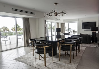 A beach bar with a counter, bar stools, and lounge chairs with umbrellas. at The Sagamore Hotel South Beach - An All Suite Hotel