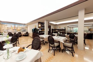 Un comedor con varias mesas y sillas, un mural en la pared y una barra de buffet al fondo.