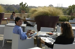 En tagterrasse med udendørs møbler, plantekasser og udsigt over bybilledet.