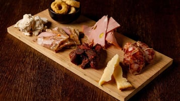 A wooden board with various food items including cheese, cured meats, and crackers.