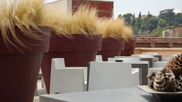 Outdoor seating with large potted plants and a view of buildings in the background.