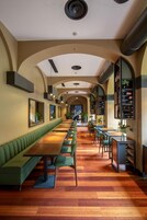 A long, narrow dining area with a green booth seating and wooden tables.