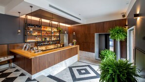 Un área de bar moderna con una barra de madera, estantes llenos de botellas de licor y un suelo con diseño.