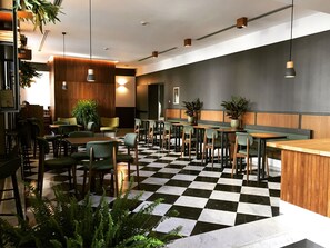 A modern restaurant with a checkered floor, wooden tables, and green chairs. - Hotel San Francesco (Rome)