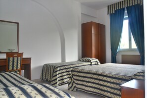 A bedroom with two beds, a wooden wardrobe, a desk, and a mirror. - Villaggio Hotel Eurolido (Falerna)