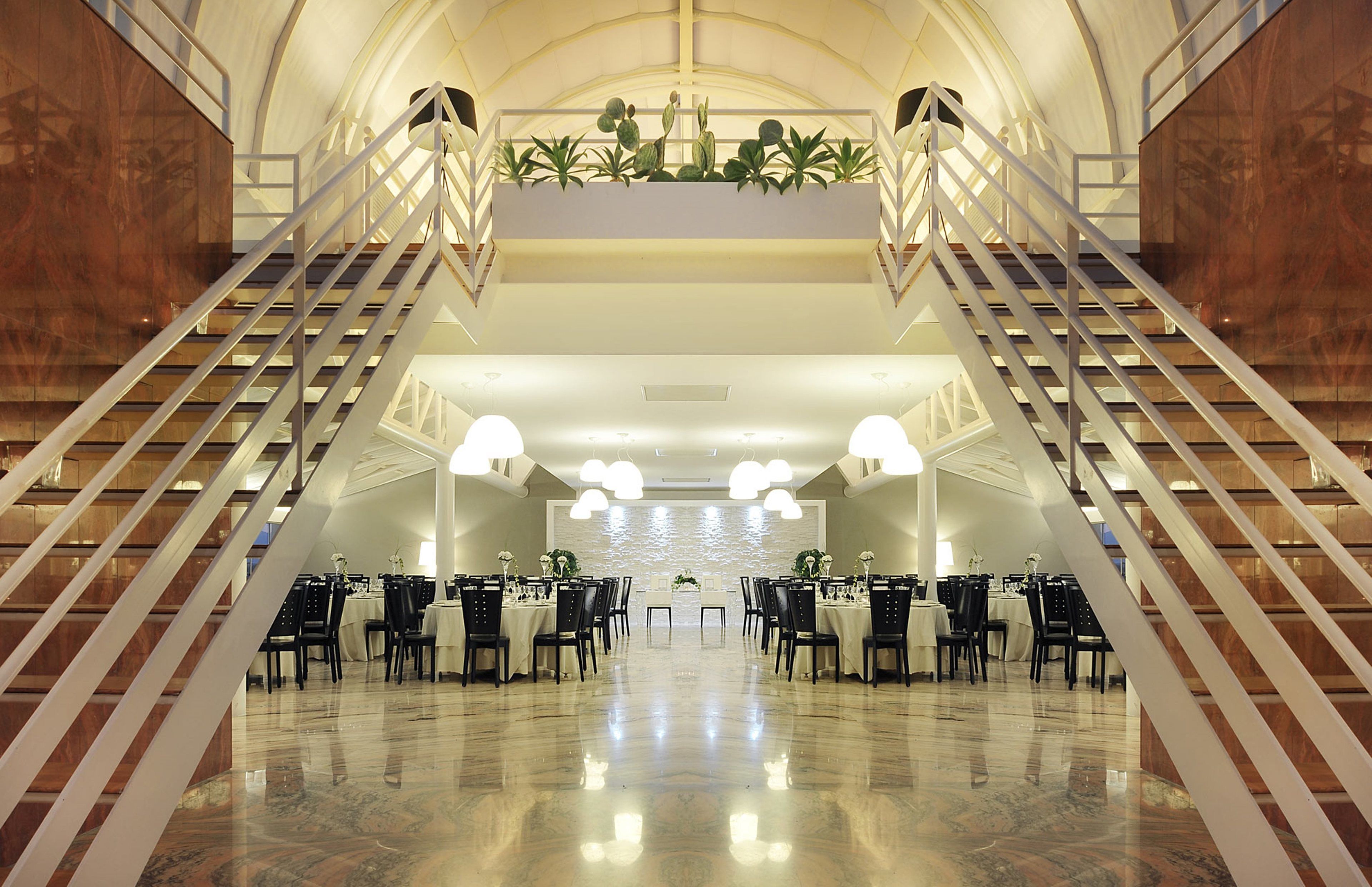 A spacious hotel lobby with a central seating area, a staircase, and a decorative ceiling.