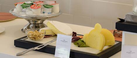 A buffet with various cheeses, fruits, and yogurt containers.