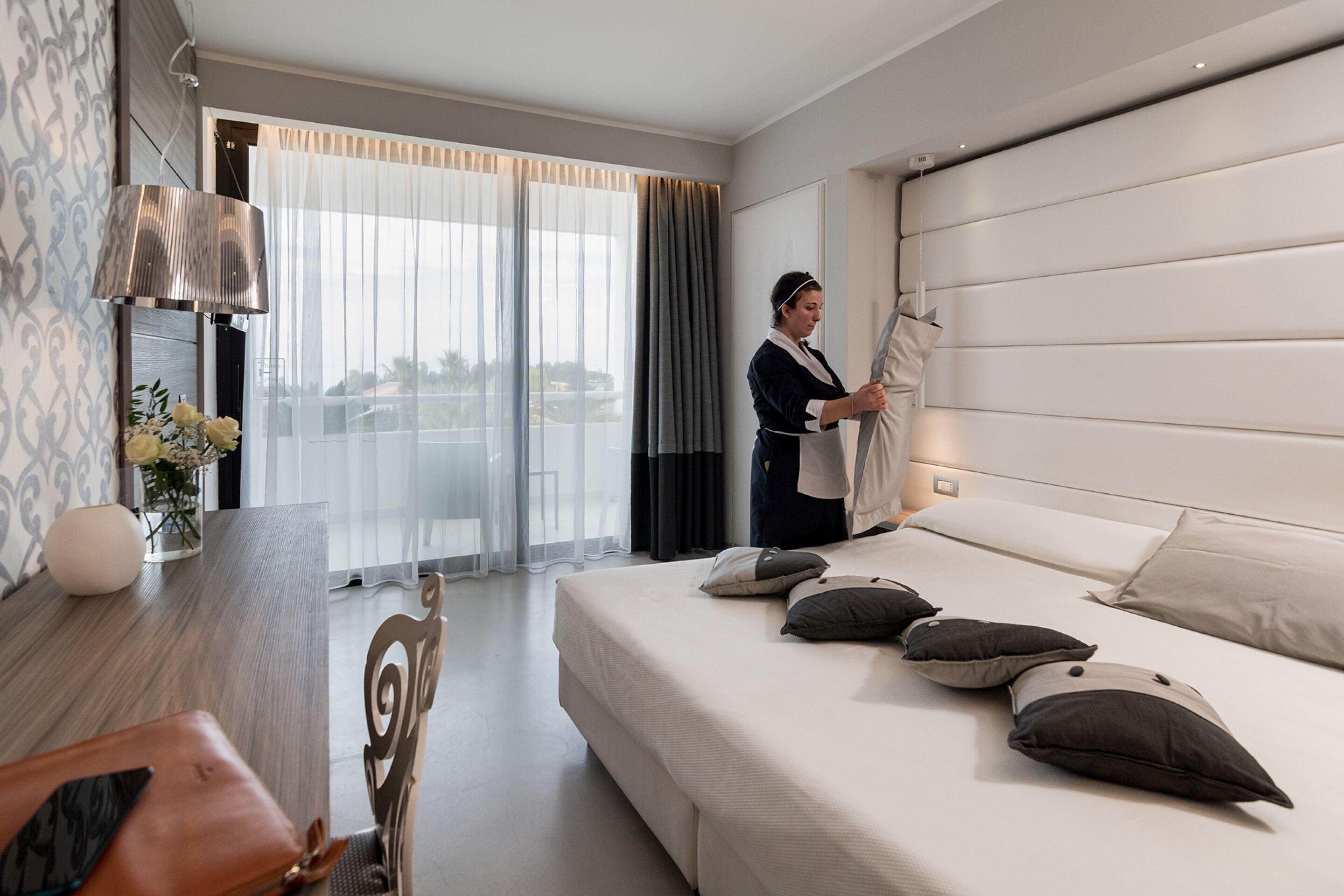 Een hotelkamer met een bed, een bureau, een stoel en uitzicht op het omliggende landschap.