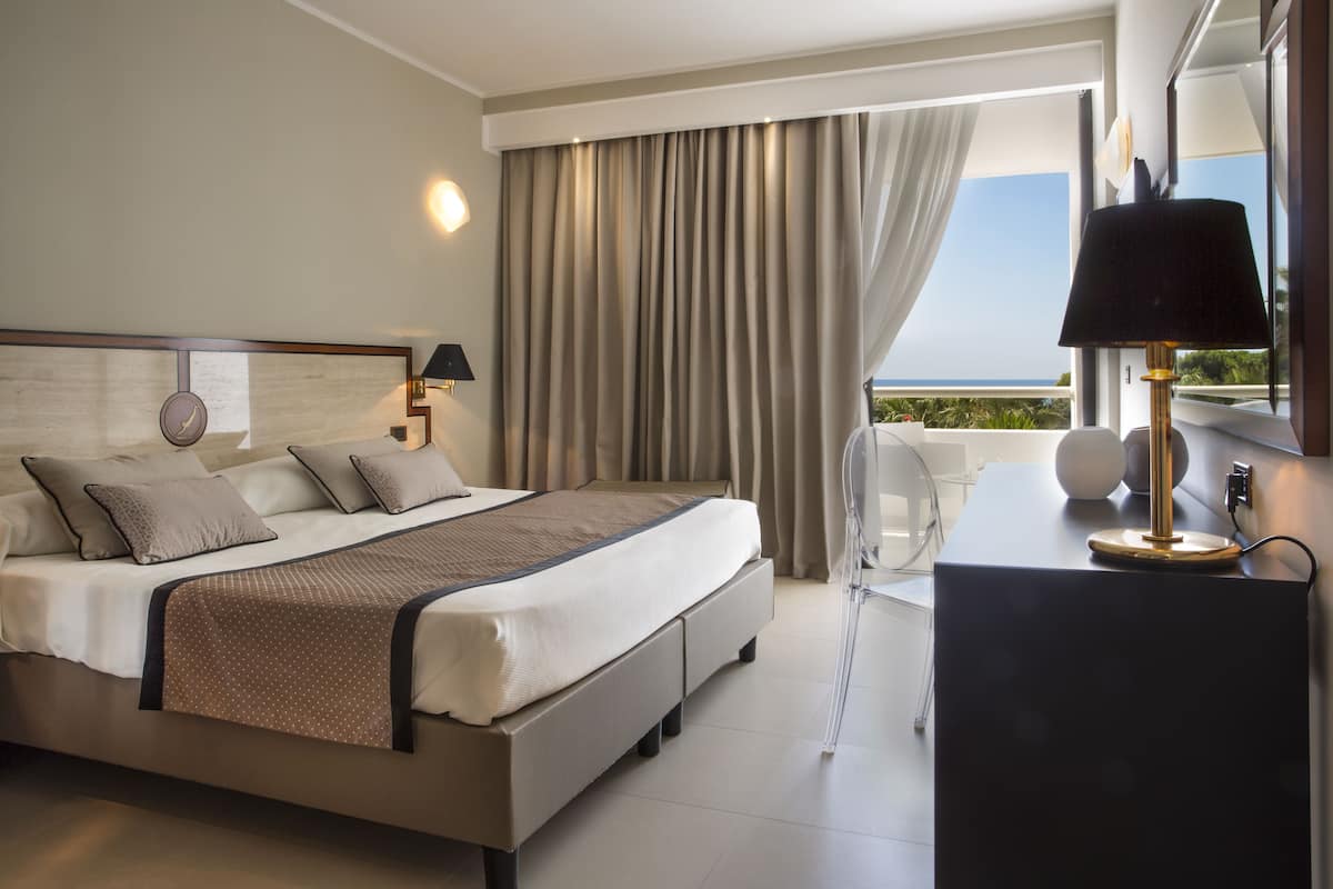 Una habitación de hotel moderna con una cama grande, un escritorio y vistas al océano.