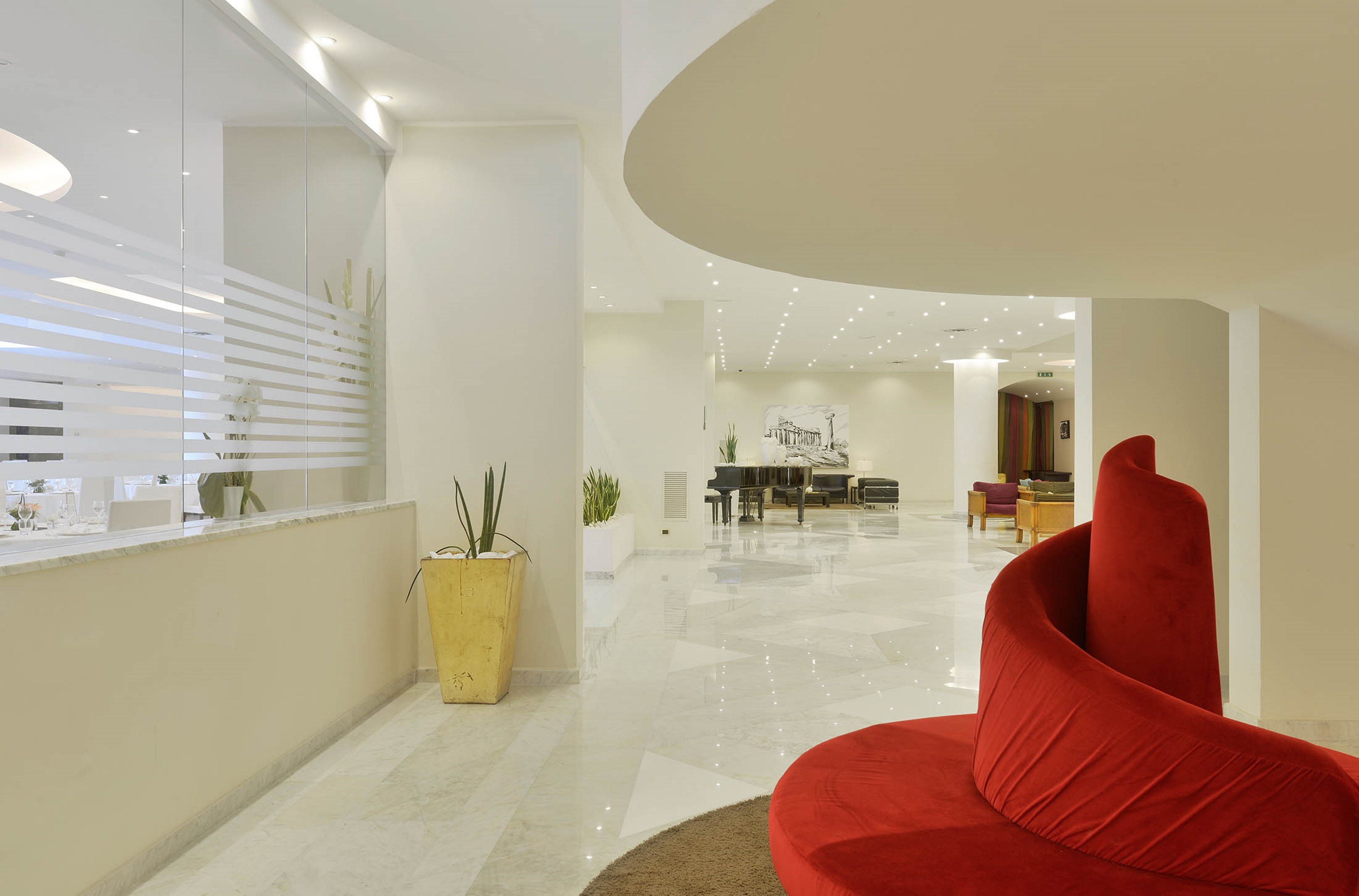 Ein modernes Interieur mit einem roten Sofa, einem Klavier und einem Essbereich.