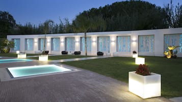 A modern outdoor area with a pool, seating, and illuminated wall panels.