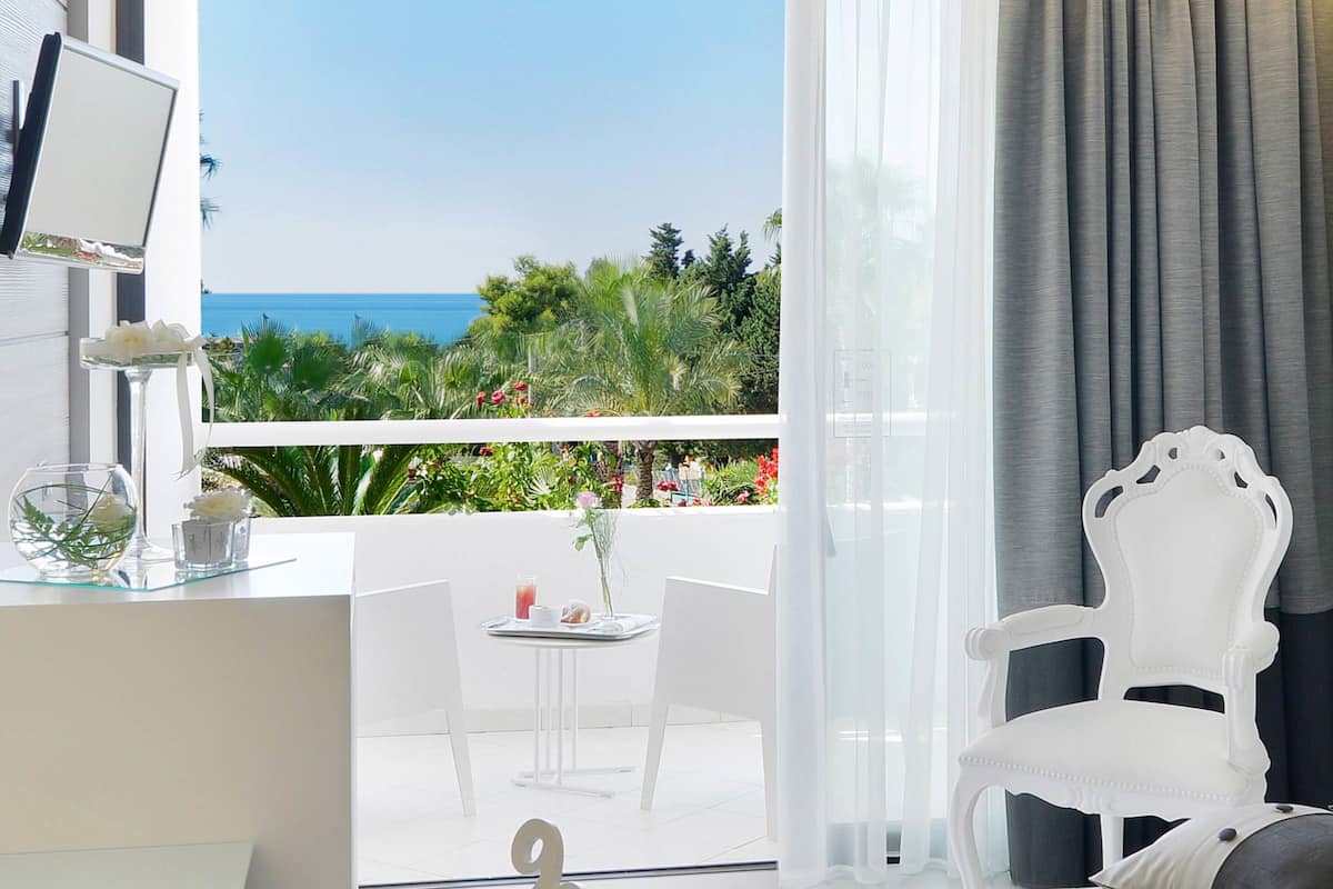 Una habitación moderna con balcón y vistas panorámicas del mar y la vegetación.
