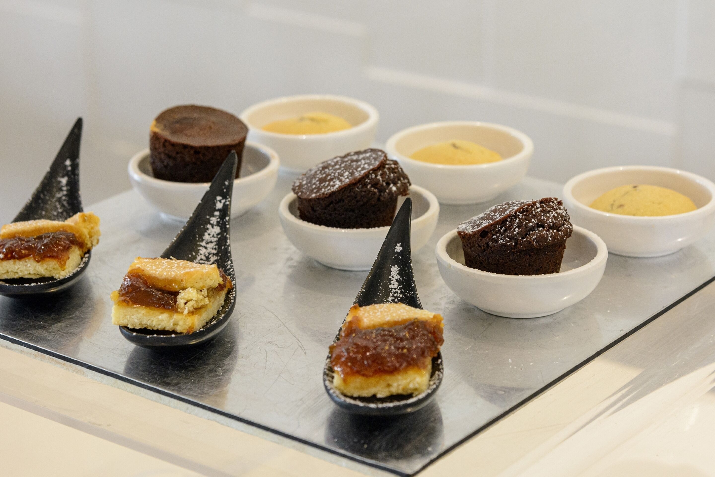 Una bandeja de postres con diversos dulces y salsas.