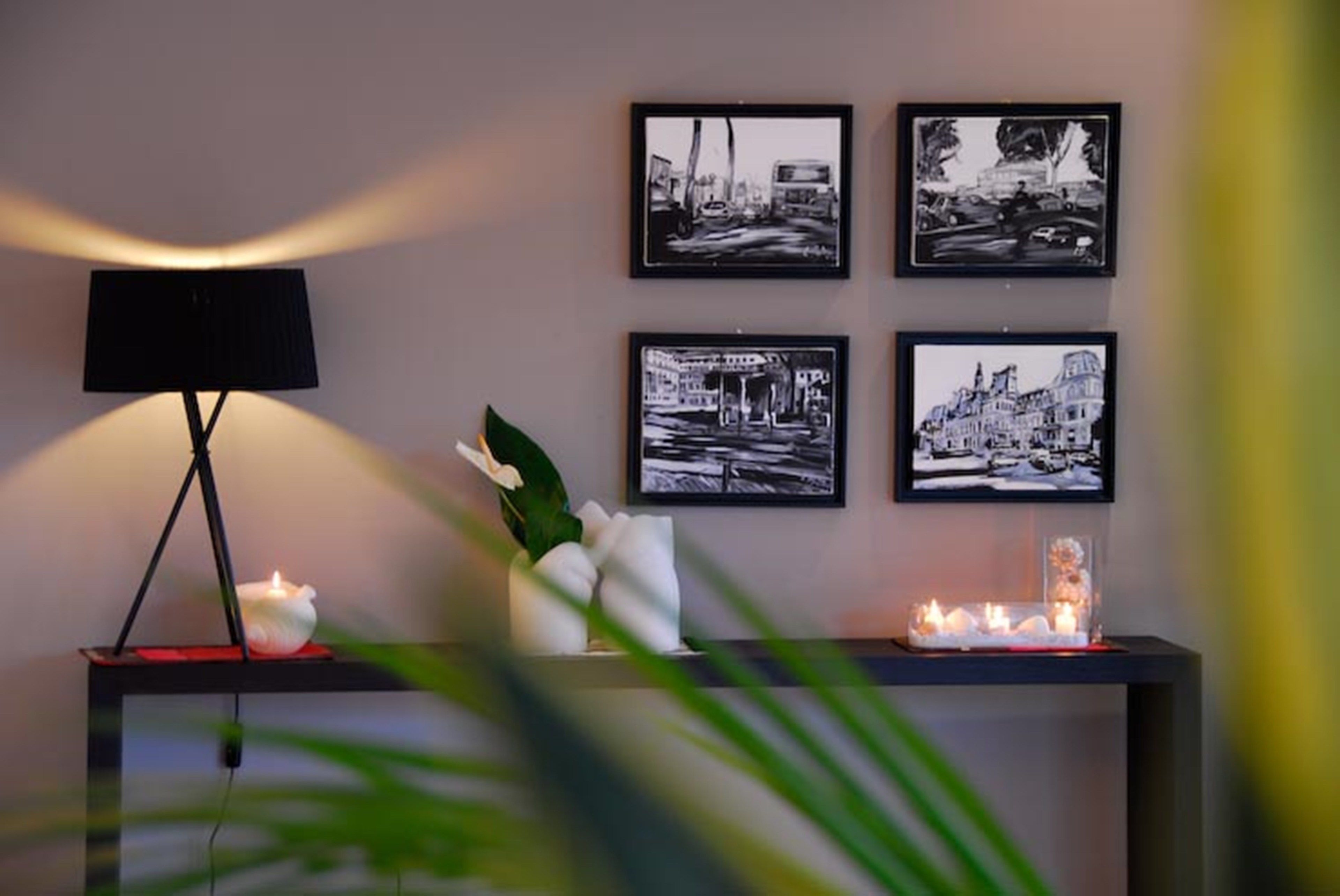 A room with a desk, a lamp, and four black-and-white photographs on the wall.