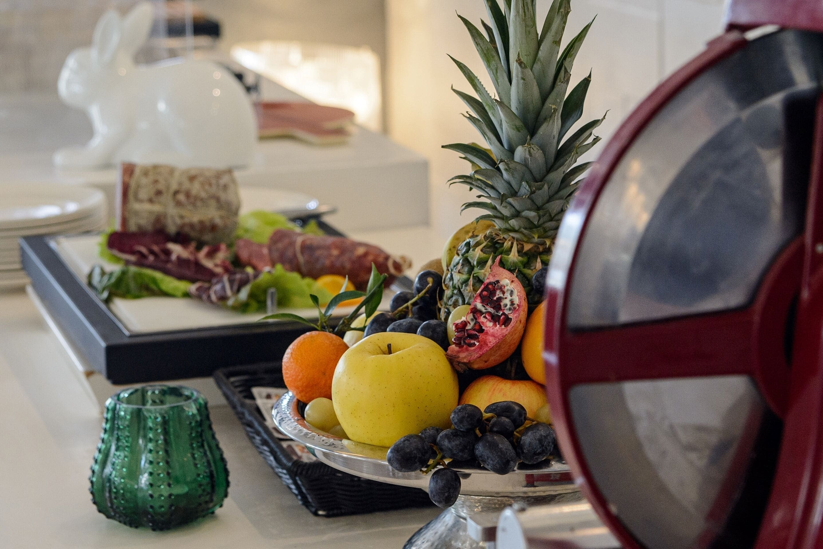 Eine Obstplatte mit Ananas, Granatapfel, Trauben und Äpfeln auf einer Platte.