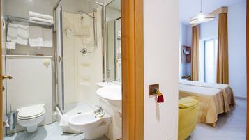 A modern bathroom with a shower, toilet, bidet, and sink.