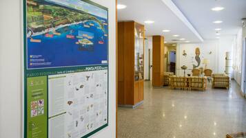 Un hall d’entrée avec une carte et des panneaux d’information, des meubles en bois et un sol carrelé.