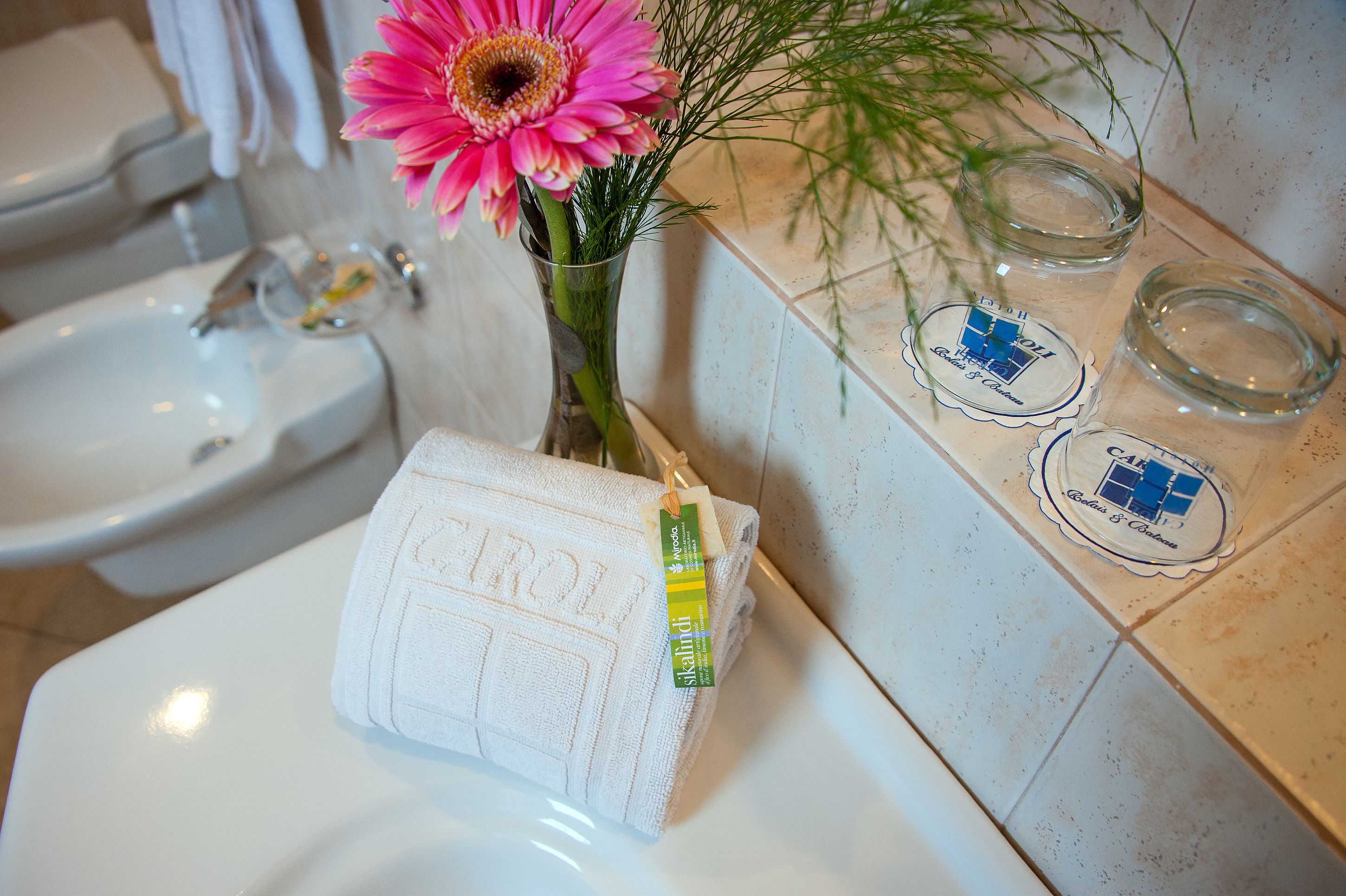 Un bagno con lavandino, WC e asciugamano con etichetta.