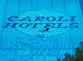 Una piscina con la inscripción "CAROLI HOTELS" escrita en el agua.