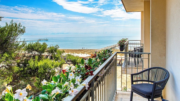 Un balcón con vista al mar, una silla y plantas en macetas.
