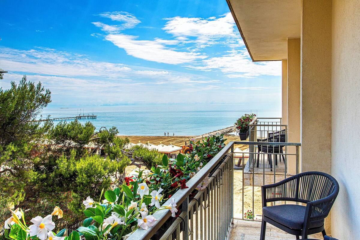 A balcony with a view of the sea, a chair, and potted plants.