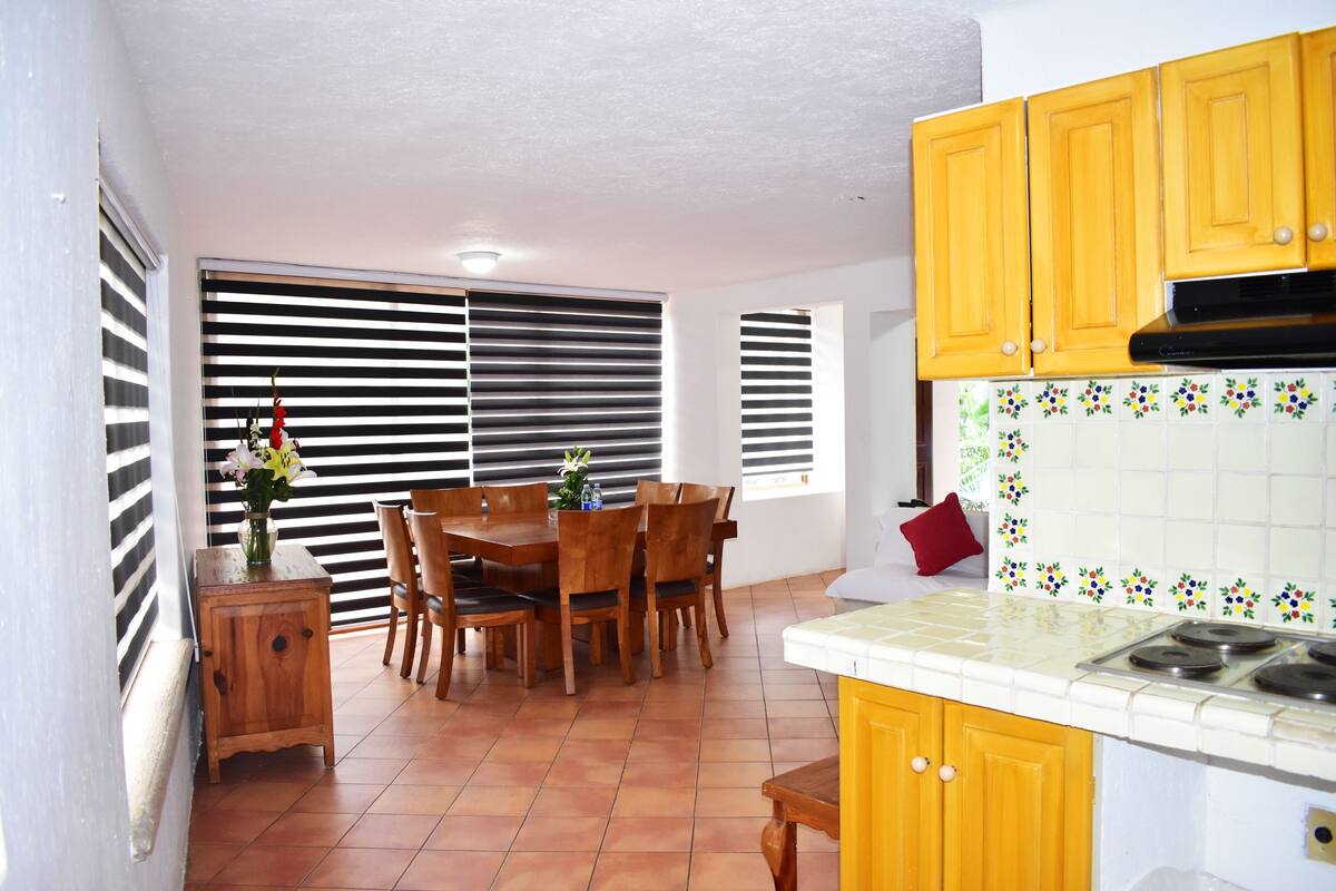 A kitchen with wooden cabinets, a tiled backsplash, and a dining area with a table and chairs.