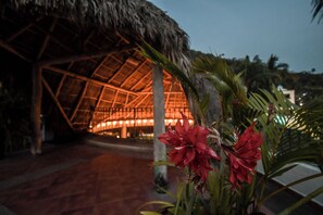 A thatched-roof building with a geometric interior structure, surrounded by tropical plants. - Hotel Casa Iguana Mismaloya (Puerto Vallarta)