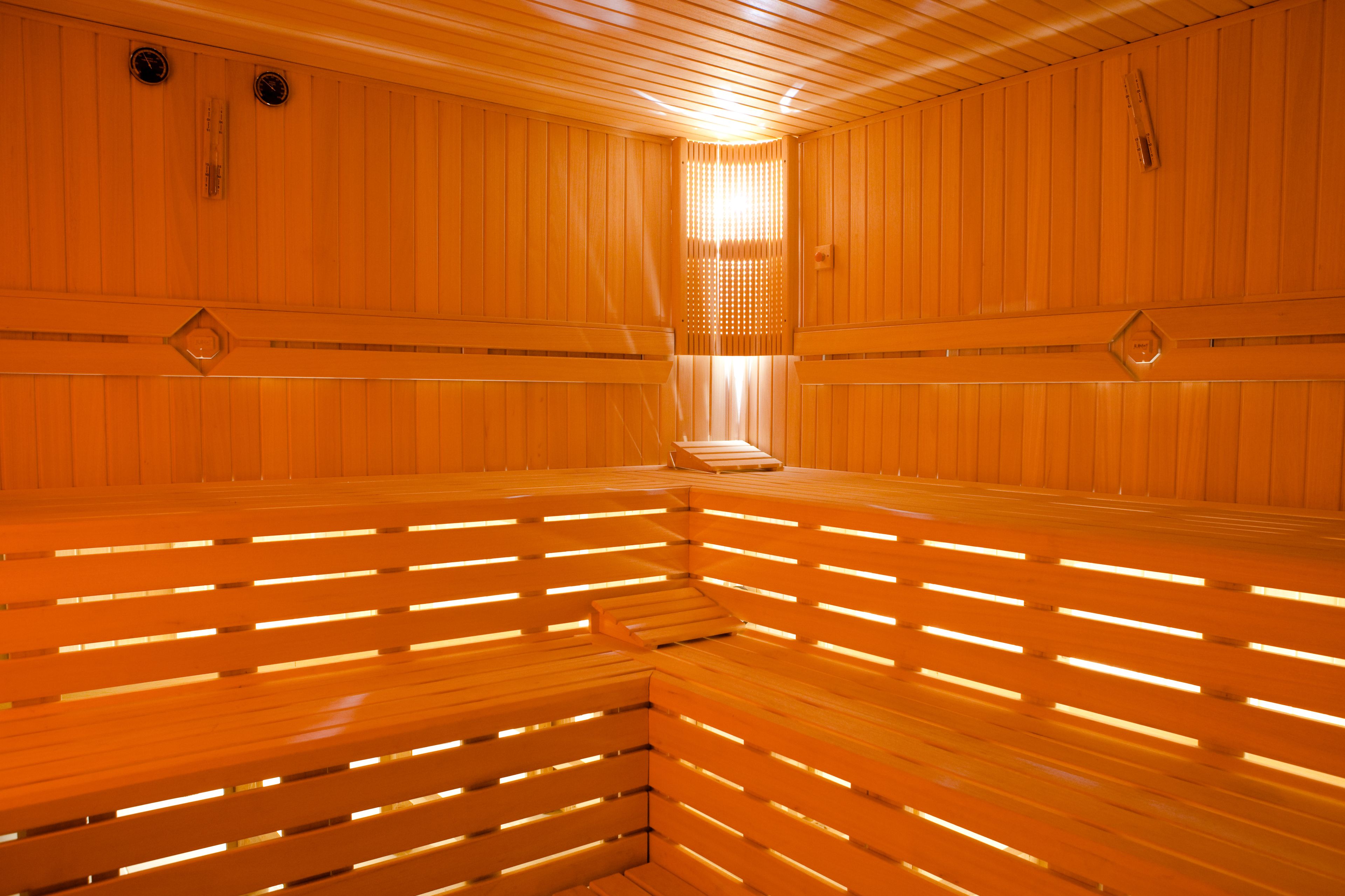 Een sauna met houten banken en een lichtbron in het midden.