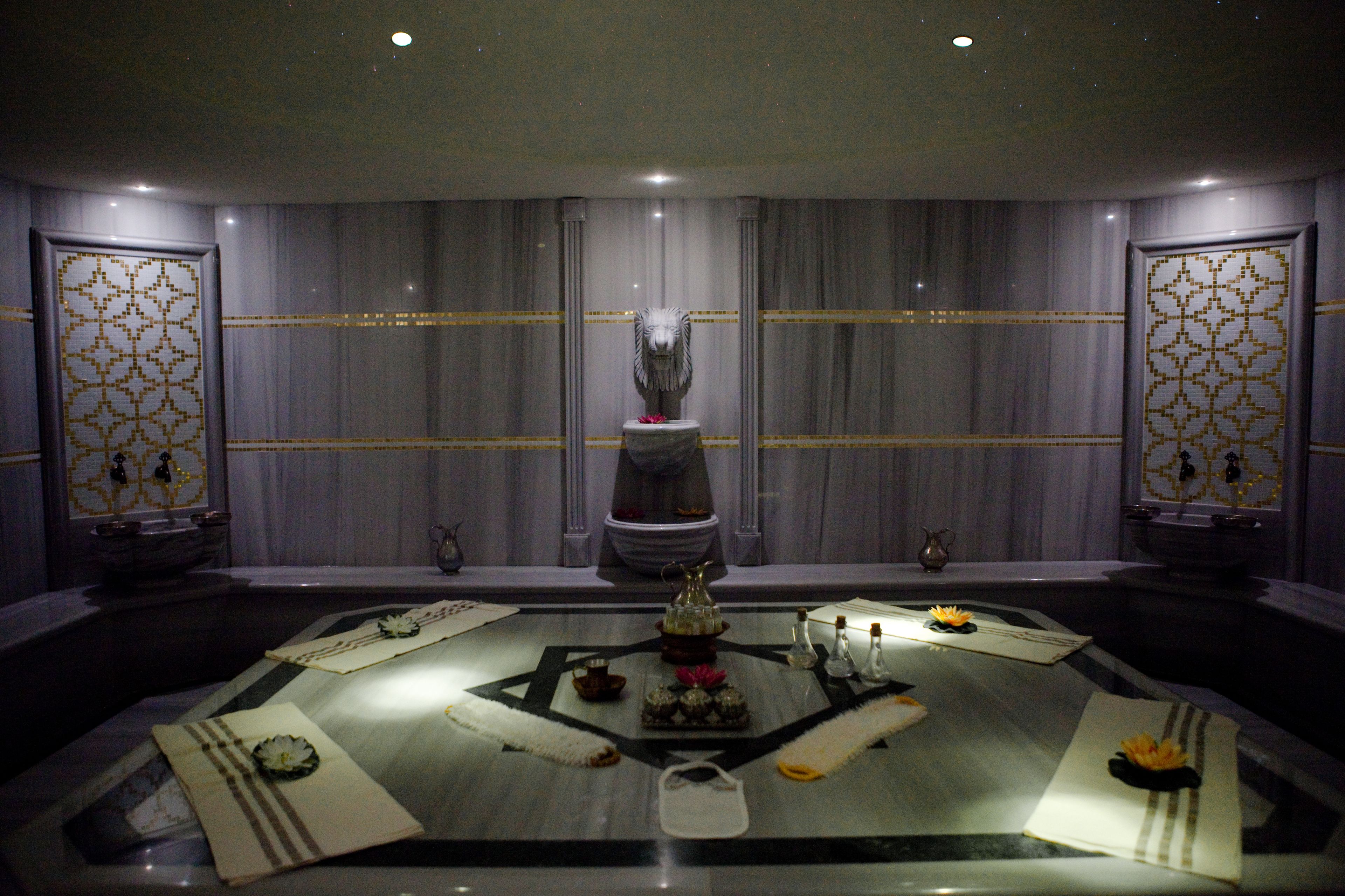 A luxurious bathroom with a central fountain, marble flooring, and decorative panels.