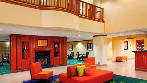 A lobby with a fireplace, seating area, and a staircase. - Fairfield Inn & Suites by Marriott Phoenix Midtown (Phoenix)