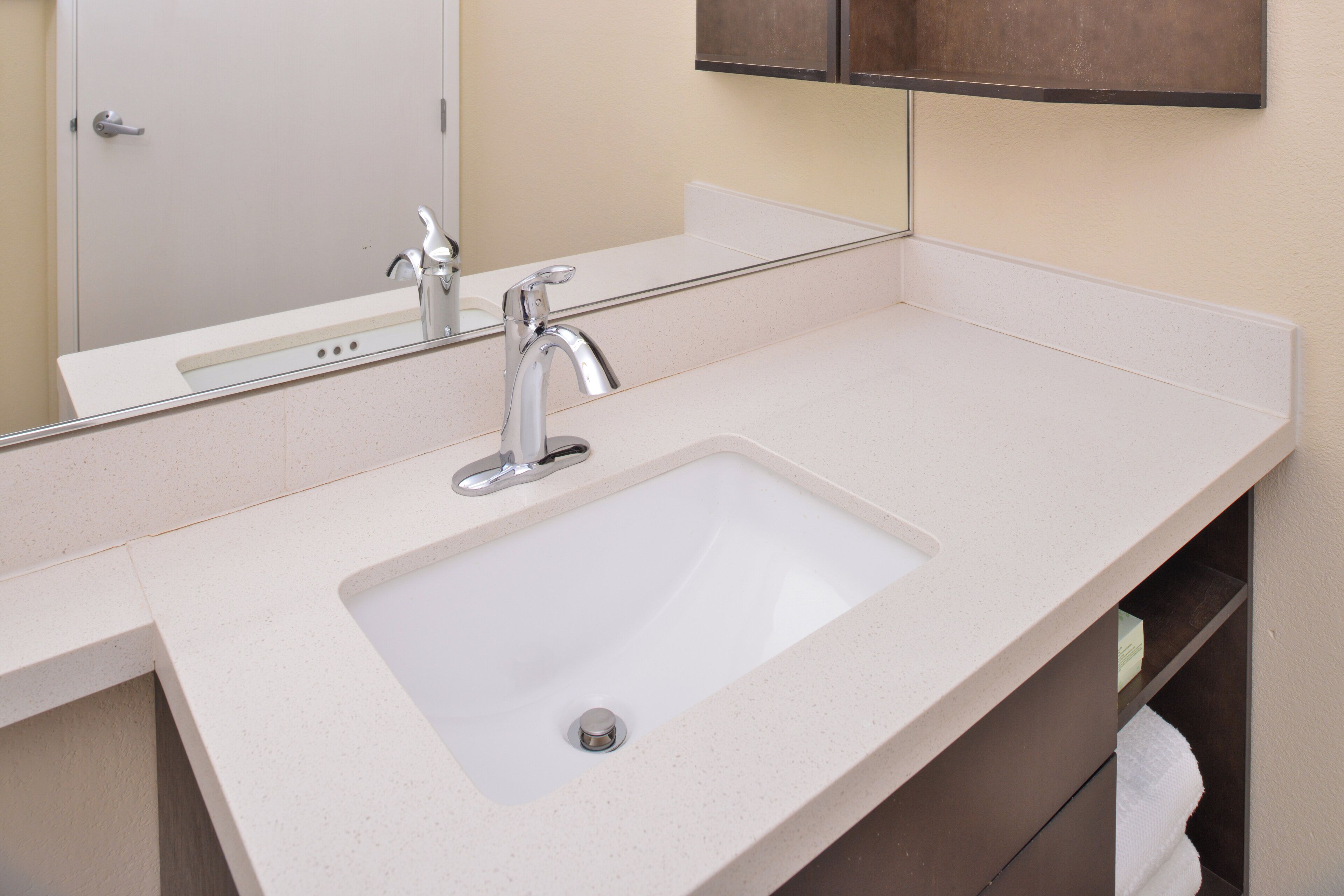 A bathroom with a white sink, a mirror, and a towel rack.