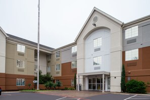 A multi-story hotel with a central entrance, large windows, and a parking lot. - Candlewood Suites Austin-Round Rock by IHG (Round Rock)
